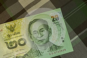 Close up of Thai banknote Thai bath with the image of Thai King. Thai banknote of 20 Thai baht on Green Scottish fabric.