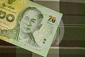 Close up of Thai banknote Thai bath with the image of Thai King. Thai banknote of 20 Thai baht on Green Scottish fabric.