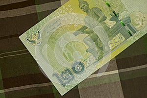 Close up of Thai banknote Thai bath with the image of Thai King. Thai banknote of 20 Thai baht on Green Scottish fabric.