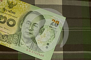 Close up of Thai banknote Thai bath with the image of Thai King. Thai banknote of 20 Thai baht on Green Scottish fabric.