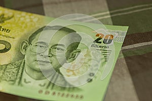 Close up of Thai banknote Thai bath with the image of Thai King. Thai banknote of 20 Thai baht on Green Scottish fabric.