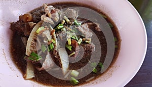 Close up Thai rice noodle with beef, stale meat, liver, cow rag, offal on wooden table and copy space on right at local street