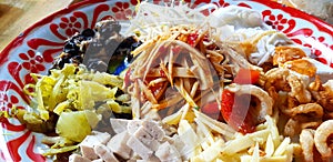 Close up Thai spicy papaya salad mixed with pork crispy, pickled vegetables, Thai pork sausage, shell and rice noodle