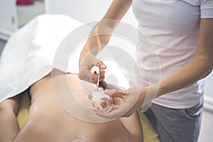 Close-up of a therapist giving cupping treatment. Female laying on chest and relaxing Cupping massage.