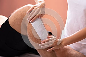 Therapist Waxing Man`s Leg