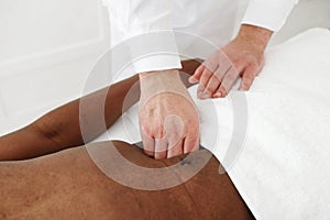 Close up of therapist hands doing visceral massage on african male abdomen on white background, copy space.