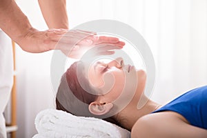 Therapist Performing Reiki Healing Treatment On Woman photo