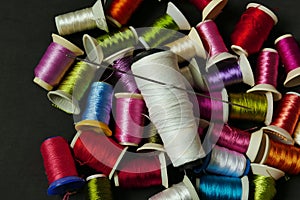 close-up there are lots of colorful spools of thread, thick sewing thread, big needle