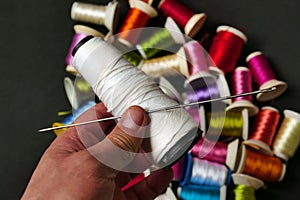 close-up there are lots of colorful spools of thread, thick sewing thread, big needle