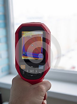 Close up thermal imaging camera inspection of window building. check heat loss. A man examines the room for heat loss.