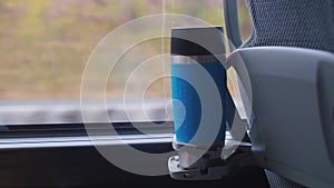 Close-up of a thermo mug of a tourist bus chair standing in a cup holder.