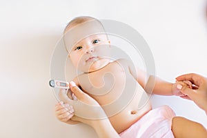 Close-up thermometer. Mother measuring temperature of her ill kid. Sick child with high fever laying in bed.