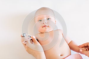 Close-up thermometer. Mother measuring temperature of her ill kid. Sick child with high fever laying in bed.