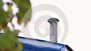 Close-up of a thickly smoking chimney on the roof of a house.