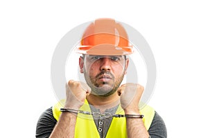 Close-up of thief builder wearing hardhat and vest handcuffed