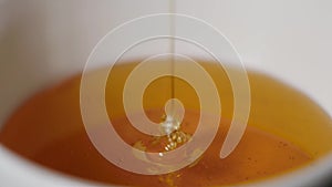 Close up of a thin honey trickle against a black background