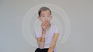 Close up thinking boy on gray background. Doubt expression concept.