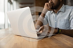 Close up thoughtful African American man using laptop, typing