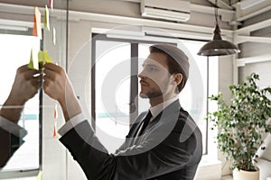 Close up thoughtful businessman adding sticky paper on board