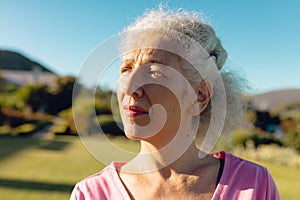 Close-up of thoughtful caucasian senior woman looking away against clear blue sky in yard