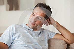 Close-up of a thoughtful man sitting on sofa