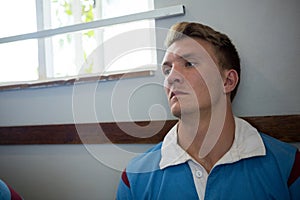 Close up of thoughtful rugby player sitting against wall