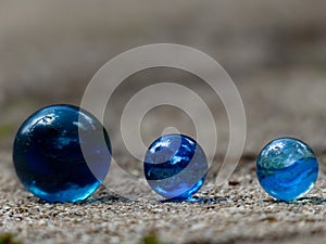 Close up of three blue glass marbles in a row with blurred background space to place text