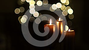 Close up of three burning candles with blurred Christmas light background. Dynamic focus, celebration of Christmas, All