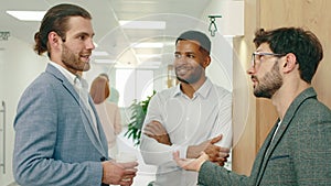 A close up of three business men with work clothes and beards having an intellectual conversation in the hall