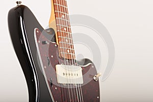 Close up of three controls on black electric guitar, studio shoot. Red tortoise shell pickguard, alder body, two single coil