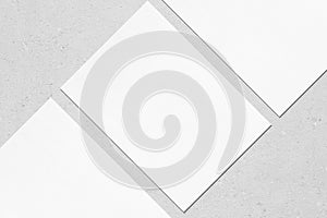 Close up of three empty white rectangle poster mockups lying diagonally on grey concrete background