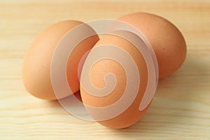 Close-up of Three fresh uncooked hen eggs on the wooden table