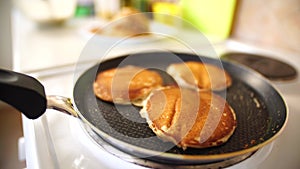 Close-up of three golden ruddy pancakes in a frying pan, light white steam.