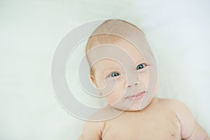 Close-up of three months old baby girl with blue eyes. Newborn child, little adorable smiling girl looking at camera