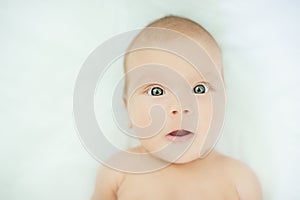 Close-up of three months old baby girl with blue eyes. Newborn child, little adorable smiling girl looking at camera