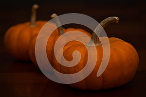 Close-up of three mini pumpkin with dark background on wooden table