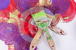 Close up three paint brushed stacked fanned out on swirl textured background purple red green