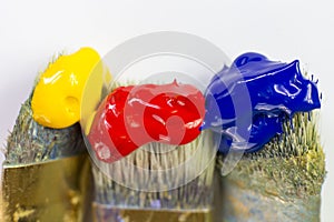 Macro three paint brushes with red, yellow and blue paint on a white background. Place for text, for banner, for site.