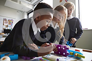 Close up of three primary school children working together with toy construction blocks in a classroom, low angle, side view photo