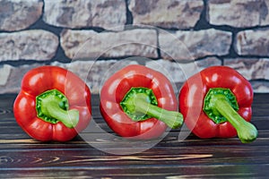 Close up of three red peppers on a wooden table