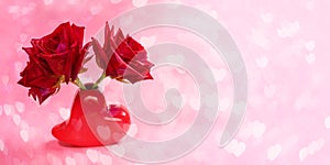 Close-up three red roses in red vase shaped heart on pink bokeh background with hearts. Valentines day or mothers day