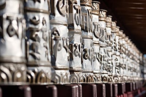 Close up of tibetan buddhist prayer wheels with the mantra `Om mani Padme Hum`.