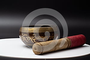 A close up of a Tibetian singing bowl with the stick lying beside it photo