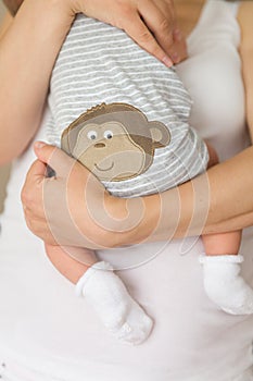 Close-up of tiny baby in socks in the hands of his mother. Young mom hugging her newborn child. Motherhood and childhood. New life