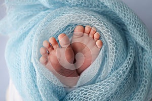 Close-up of tiny, cute, bare toes, heels and feet of a newborn girl, boy. Baby foot on blue soft coverlet, blanket.