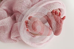 Close-up of tiny, cute, bare toes, heels and feet of a newborn girl, boy in pink