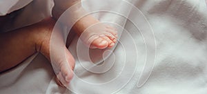 Close-up tiny newborn baby feet on a white blanket