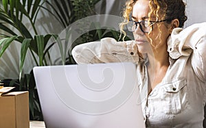 Close up of tired businesswomann in front of a computer. Exhausted female worker online job. One lady touching and massaging her