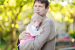 Close-up of tired young father with crying baby girl. Dad with daughter outdoors, love. Tiny child crying. Bonding