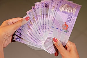 Close up to 100 Ringgit Malaysia in females hand with red finger nails